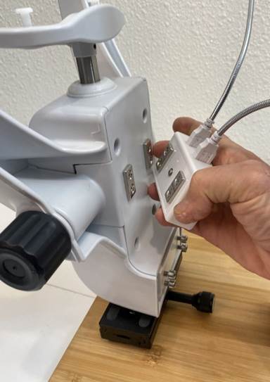 A hand holding a white device
Description automatically generated